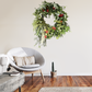 Decorative wreath hanging on a wall above a modern chair in a living room.